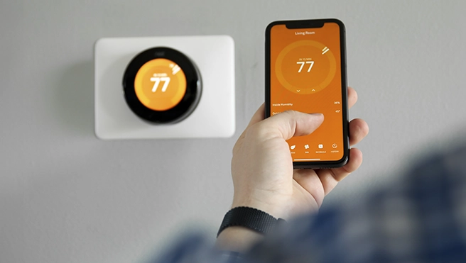 A person adjusting a smart thermostat using a smartphone app.