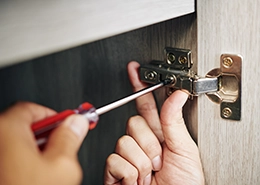 Mr. Handyman repairing hinge on door.