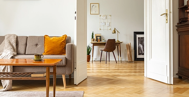 Cozy living room featuring a beige sofa with an orange cushion, a wooden table.