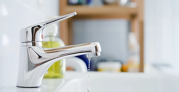 Close-up of a tap running water into a washbasin.