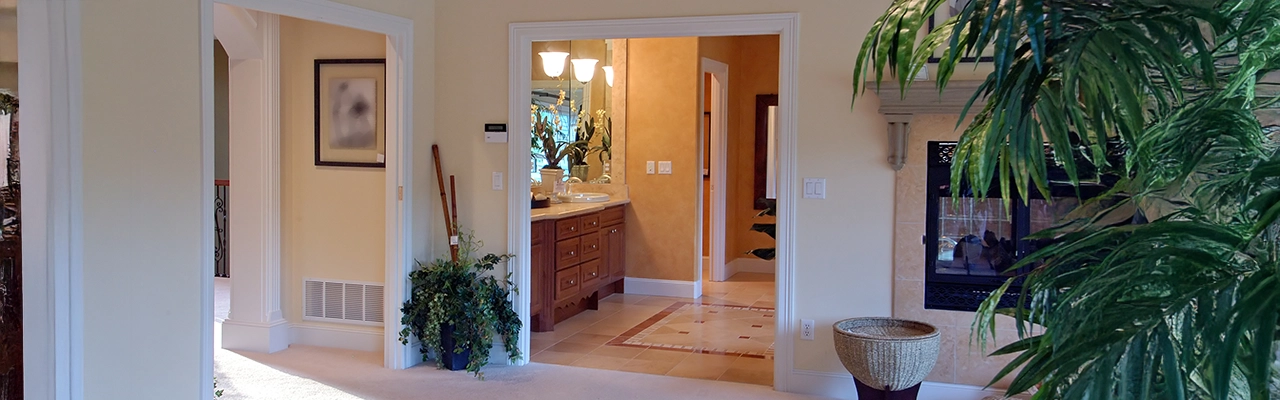 Bright, airy hallway leading to a stylish bathroom with wooden cabinets.