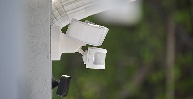 A white motion sensor light mounted on a wall.