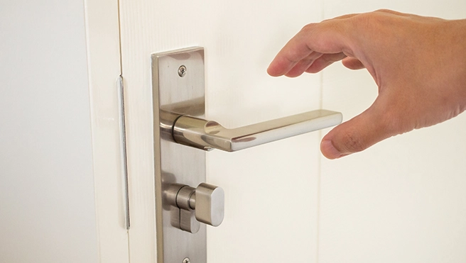 Person reaching for a door handle.