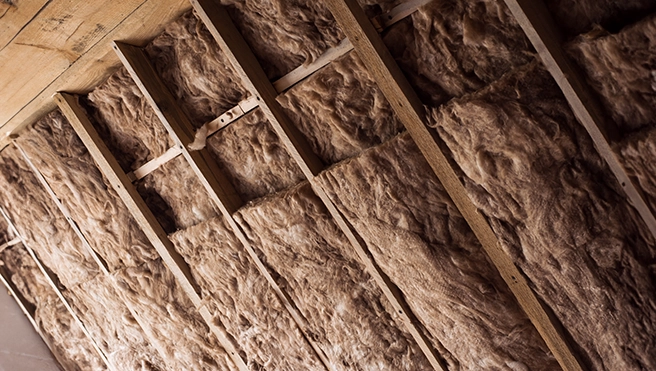 Insulation batts snugly fit within wooden framing.