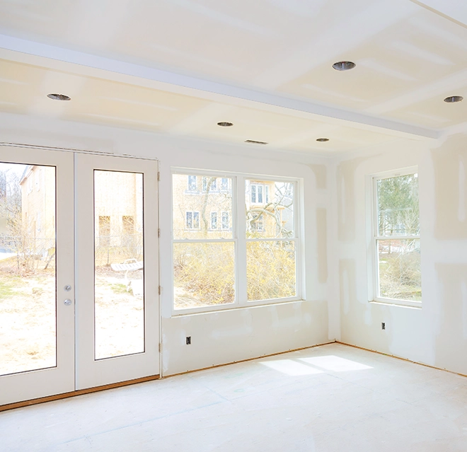 Unfinished room featuring two large windows and double doors.