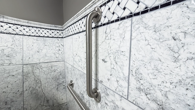 Close-up of a stainless steel grab bar mounted on elegant marble tiles.