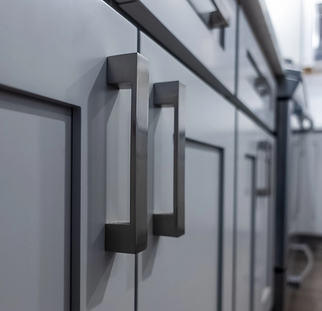 Modern metallic cabinet handles on light gray kitchen cabinets.