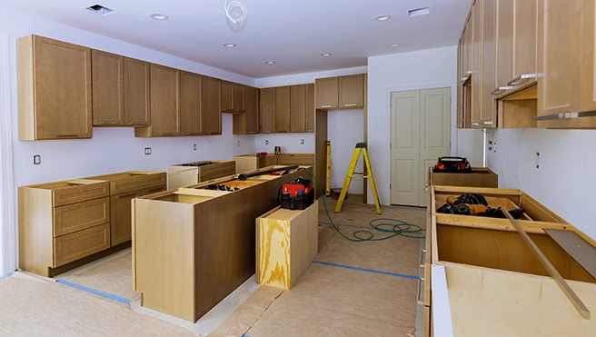 Light-filled kitchen under renovation, featuring unassembled wooden cabinets.
