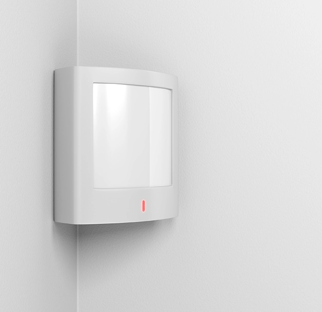 A white motion sensor mounted on a corner wall.