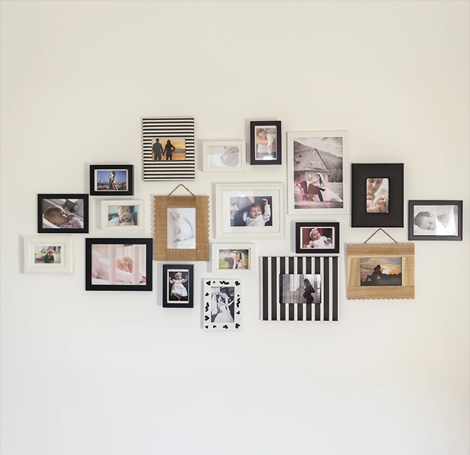 A gallery wall featuring a diverse arrangement of framed photographs on a white background.