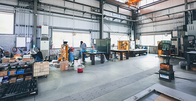 Workers engaged in manufacturing tasks in a modern workshop with tools and organized materials visible.
