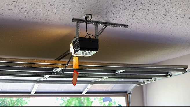 A ceiling-mounted garage door opener with a power cord.