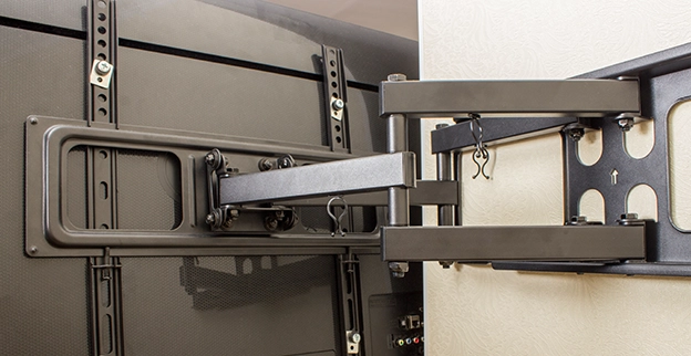 A close-up of a TV wall mount showcasing its adjustable arm connected to the back of a flat-screen television.
