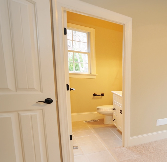 View of a bright yellow bathroom through an open door.