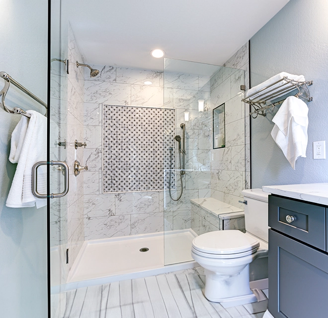 Modern bathroom featuring a glass shower, marble tiles, a white toilet, and elegant fixtures, creating a stylish and inviting space.