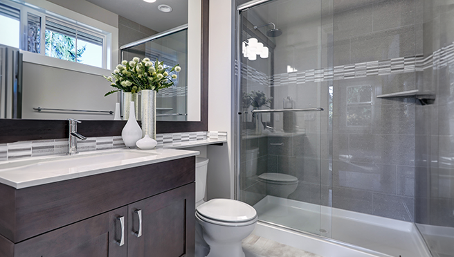Modern bathroom featuring a glass shower, sleek vanity with a vase of flowers and contemporary finishes.