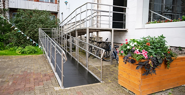 A wheelchair ramp with metal rails leads to a building entrance.