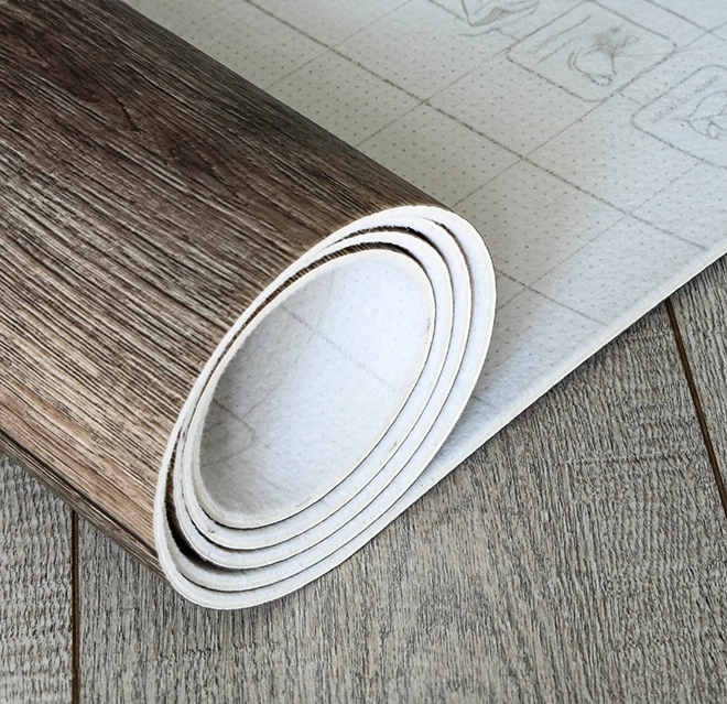 Close-up of a rolled-up vinyl flooring sample with a wood-like texture.