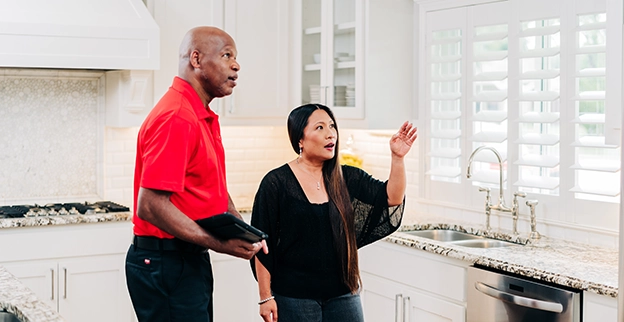 A handyman discussing about the kitchen cabinet with the customer.