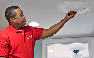 A Mr. Handyman technician spackling a ceiling.