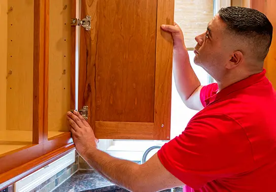 A Mr. Handyman technician fixing a cabinet.