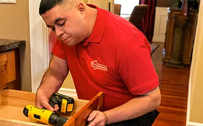 Mr. Handyman technician fixing a drawer with a drill.