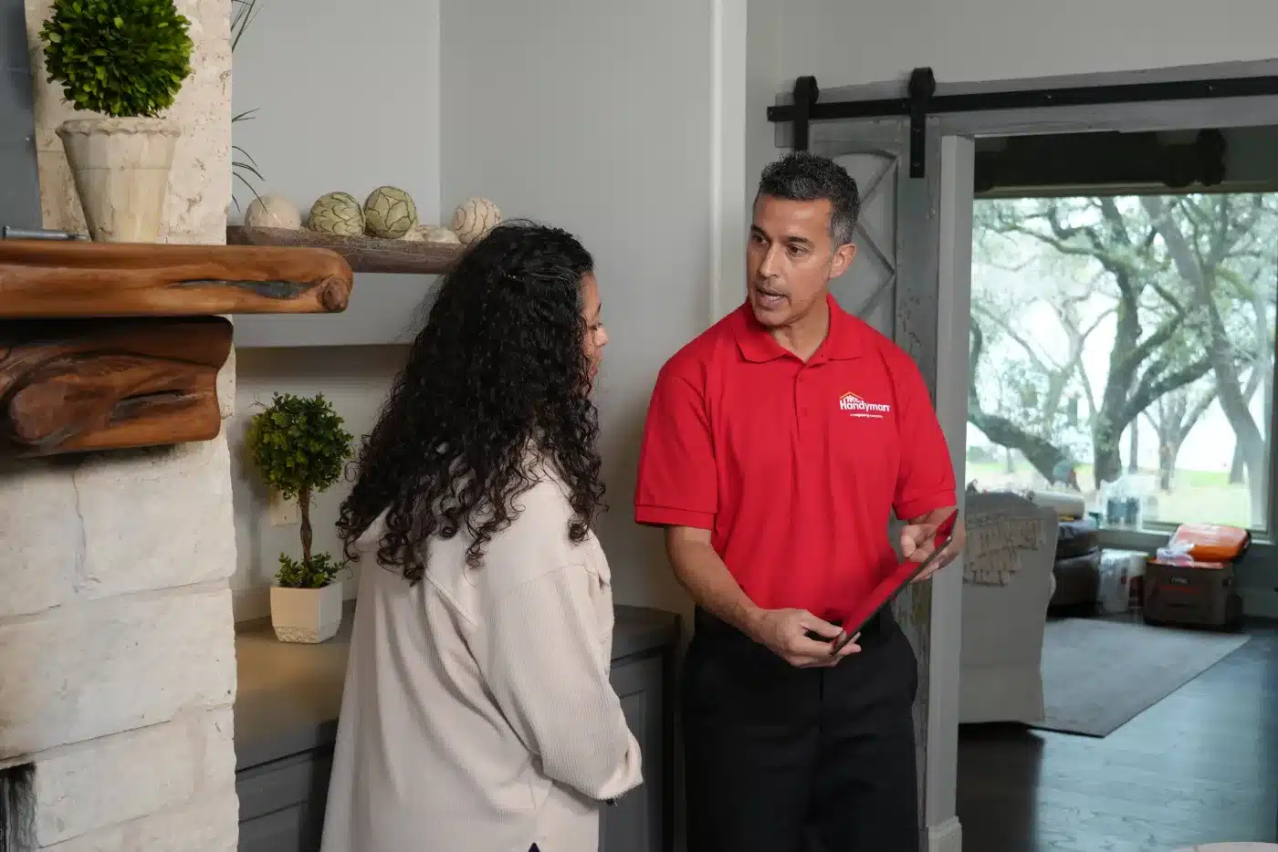 A Mr. Handyman service professional consulting with a homeowner beside an interior sliding door.