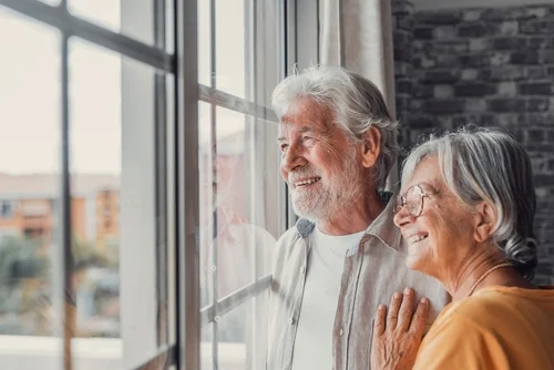 Senior couple looking out of the window.