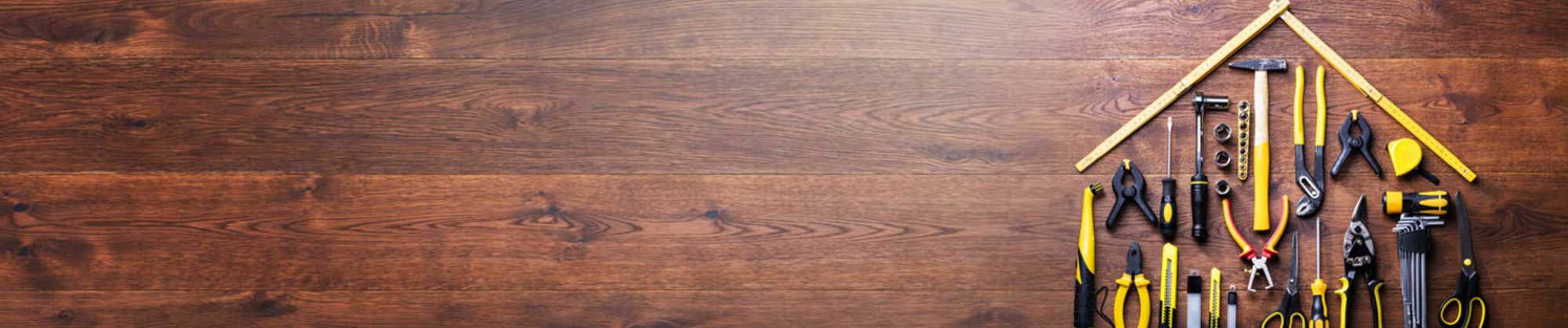 Wooden floor with tools placed together in the shape of a house. 