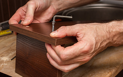 Handyman assembling drawer with allen wrench.