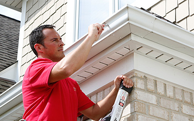 Handyman installing gutter system on home.