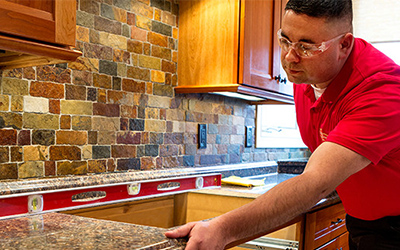 A Mr. Handyman technician fixing a drawer with a drill.