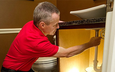 handyman installing drain pipe to sink