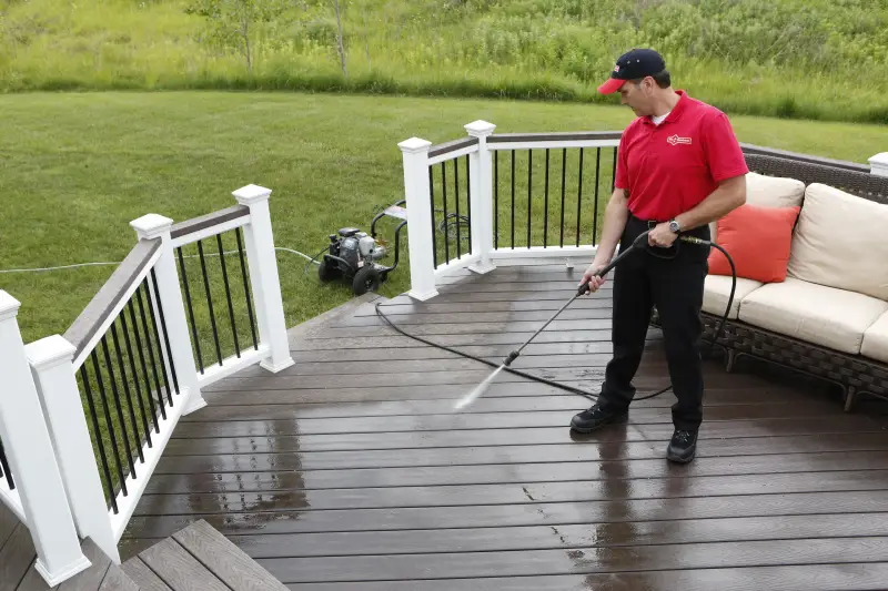 Handyman power washing wood deck.